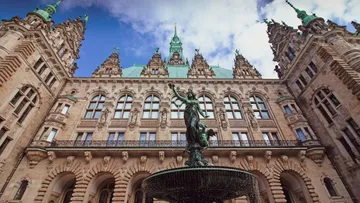 Brunnen stands in front of a magnificent historic building.