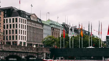 Moderne Gebäude stehen neben Fahnen an einem Wasserweg.