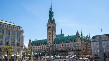 Stadtgebäude mit grünem Dach unter blauem Himmel.