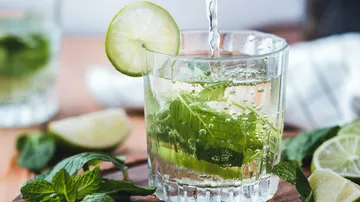 Glas mit Minze wird mit sprudelndem Wasser gefüllt.