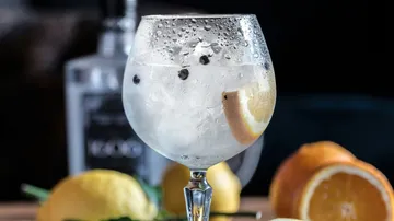 Ein Glas mit kaltem Getränk, Eis und Zitrone.