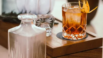 Ein Glas mit Alkohol steht auf einem Holztisch.