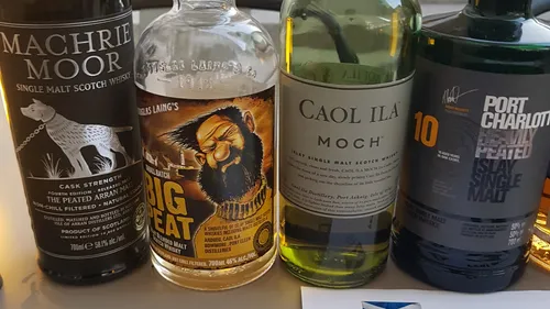 Five whiskey bottles stand side by side on a table.