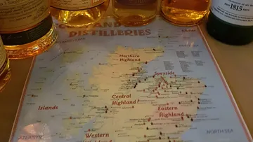 Map view, surrounded by whiskey bottles, shows distilleries.