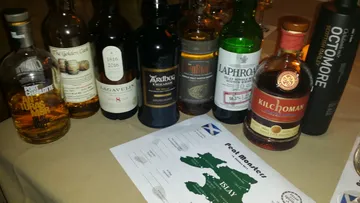 Eight bottles of whiskey are on a table with a card.