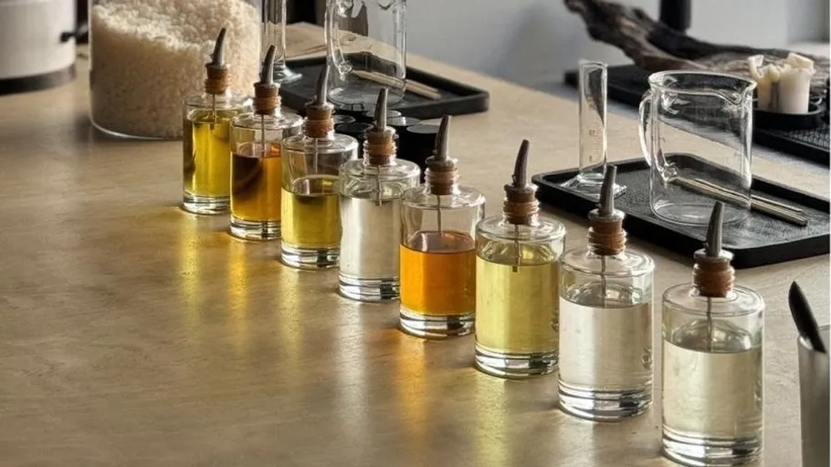 Ten glass bottles with various oils on a table.