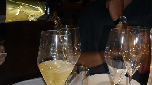 Sparkling wine is poured into glasses surrounded by guests.