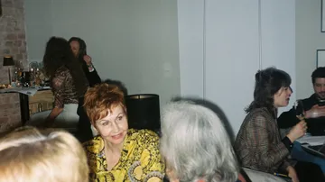 Eine Frau lächelt in einer geselligen Atmosphäre mit anderen.