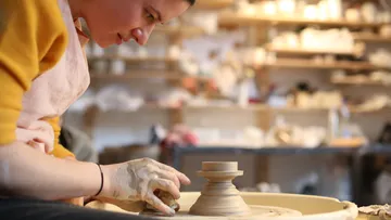 Pottery sculpting clay on a potter's wheel in a workshop.