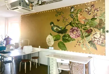 Grüne Vögel sitzen auf einer schönen Wandmalerei in einem Atelier.