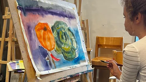 Artist painting vegetables on canvas in studio.