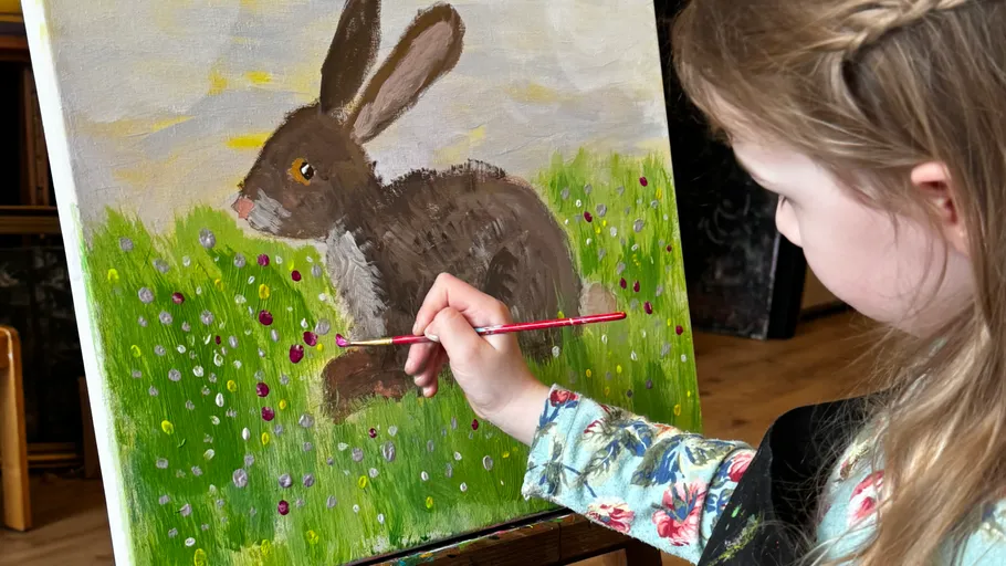 Child painting a rabbit on canvas.