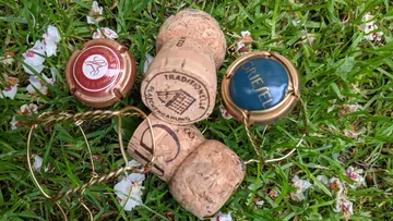 Corks lie on grass surrounded by flower petals.