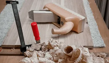 Holzspäne liegen auf einem Tisch, während Werkzeuge bereit sind.