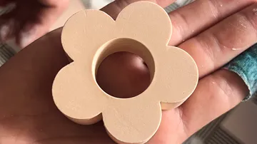 Blumenförmiger Holzring liegt in einer Hand.