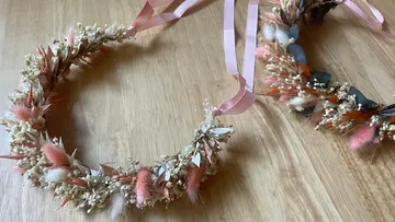 Zwei Blumenkränze liegen auf einer Holzoberfläche.