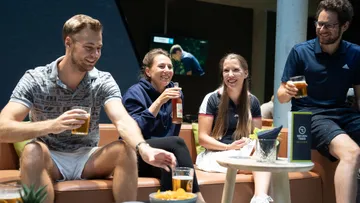 Vier Personen sitzen zusammen, lachen und trinken Bier.