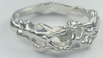 Silberring mit menschlichen Figuren, künstlerisch miteinander verbunden.