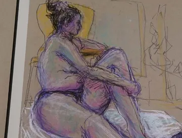 Seated person hugging legs in a room.