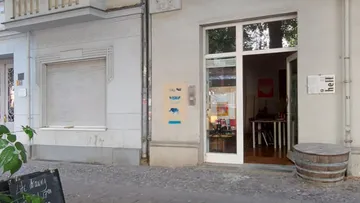 Eingang eines Geschäfts mit offener Tür, umgeben von Pflanzen.