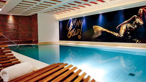 Innenpool mit Holzliege, Wandkunst und ruhiger Atmosphäre.