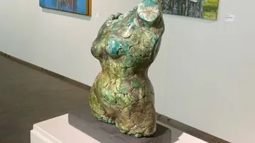 Skulptur eines weiblichen Körpers steht im Ausstellungsraum.