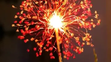 Glowing fireworks explode in a dark environment, radiant sparks.