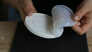 Ein weißer Silikonform wird vom Untergrund abgehoben.