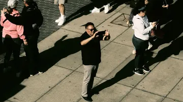 Mann fotografiert aus einer Gruppe auf einem Bürgersteig.