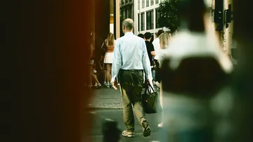 Man walks with a bag on a busy city street.