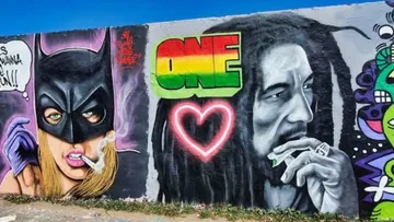 Wandgemälde zeigt Batwoman und Bob Marley mit Herz.