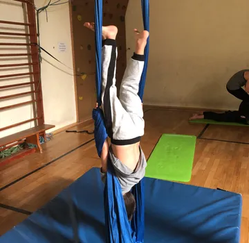 A child hangs upside down in a room in blue cloths.