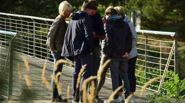 Sechse Personen stehen zusammen und schauen auf ein Gerät.