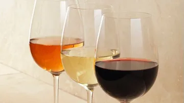 Drei Weingläser mit unterschiedlichen Weinsorten stehen nebeneinander.