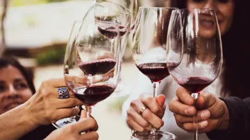 Gläser mit Rotwein stoßen an, um zu feiern.