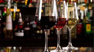 Drei Weingläser stehen hinter der Bar mit Getränken.