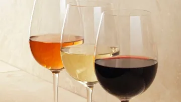 Drei Weingläser mit verschiedenen Weinsorten vor neutralem Hintergrund.