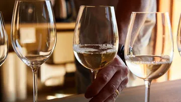 Weißwein wird in Gläsern auf einem Tisch serviert.