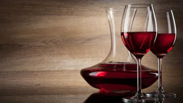 Red wine in a carafe and two glasses on wood.