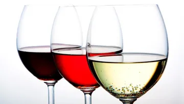 Three wine glasses with different wines are placed next to each other.