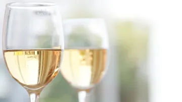 Zwei Gläser mit Wein stehen in einem hellen Raum.