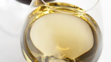 A glass of white wine is placed against a dark background.