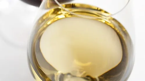 White wine in a glass, reflecting light, relaxed atmosphere.