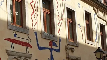 Wandmalerei mit bunten Figuren und Fenstern in der Stadt.