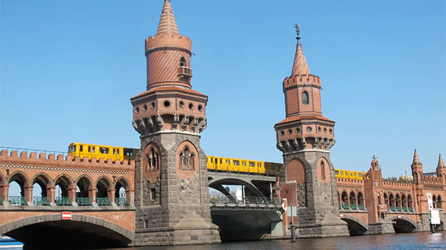 Two towers on a bridge while a train is running.