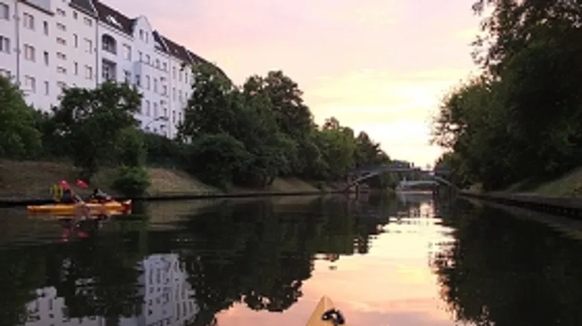 Kayak on calm water next to trees and buildings.