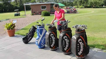 Golfspielerin sortiert Schläger in der Golfplatzumgebung.