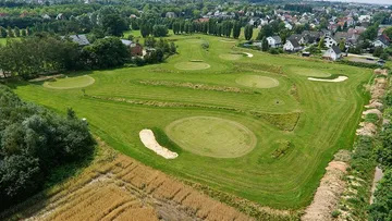 Grünflächen mit Golfzügen in einer ländlichen Umgebung.