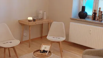 Three chairs are placed around a table in a bright room.