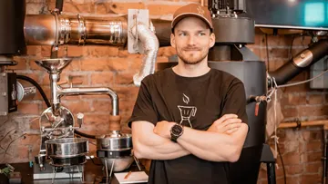 Mann steht vor einer Kaffeemaschine in einem Café.